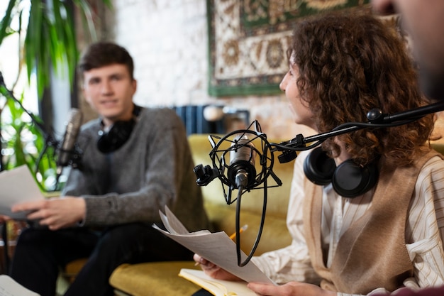 Gratis foto mensen die een podcast uitvoeren met microfoons en koptelefoons vanuit de studio