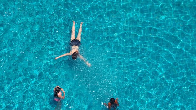 Mensen die in het hotelzwembad zwemmen met blauw water en zonlicht reflecteren erop en de kijkhoek van bovenaf.