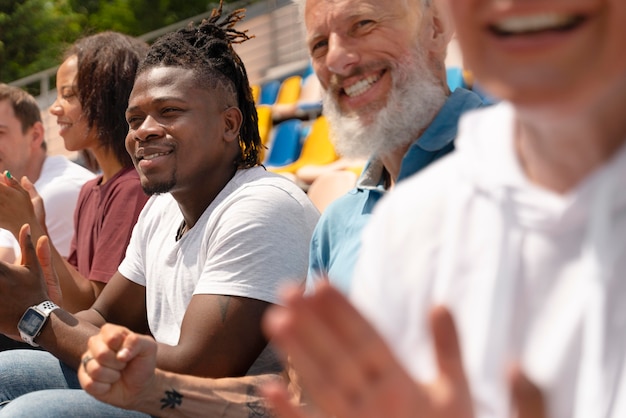 Mensen die op een zonnige dag naar een voetbalwedstrijd kijken