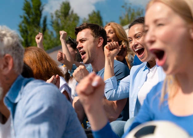 Gratis foto mensen die op een zonnige dag naar een voetbalwedstrijd kijken