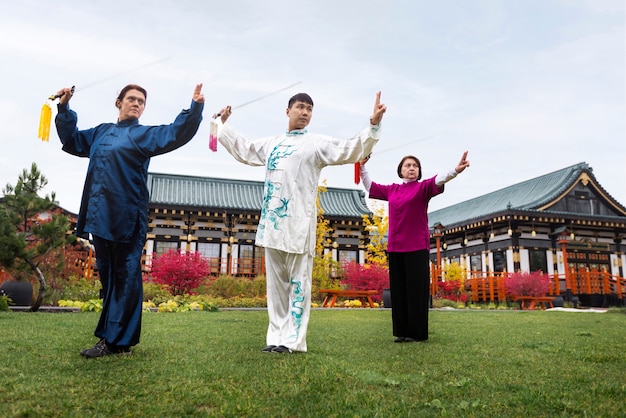 Gratis foto mensen die tai chi buitenshuis beoefenen, volledig geschoten