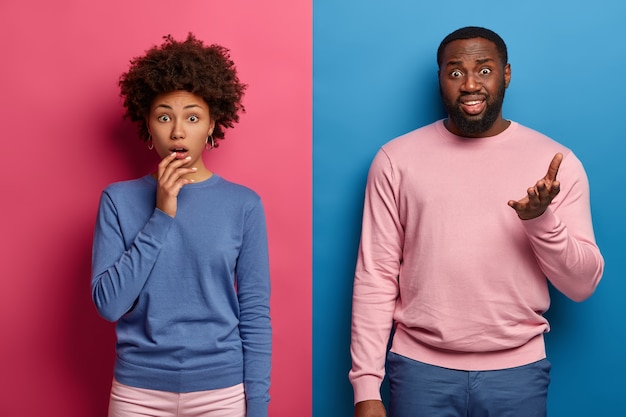 Mensen en emoties. Verbaasd Afro-Amerikaans meisje hapt van verwondering, ontevreden man met baard steekt handpalm op