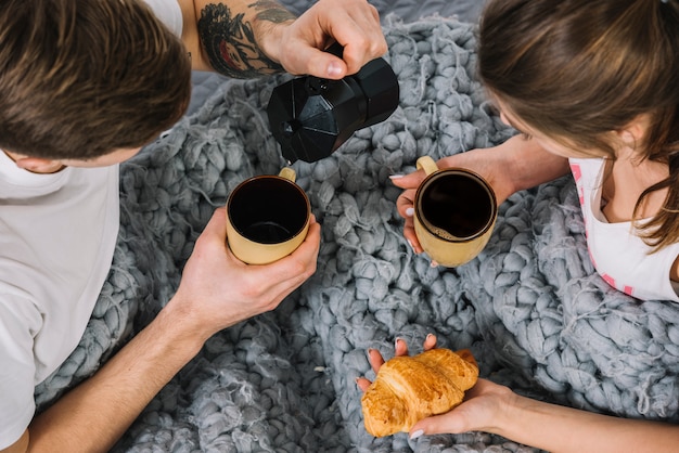 Gratis foto mensen gietende koffie in kop op bed