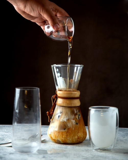 Mensen gietende stroop op koffie die met melk wordt gemengd