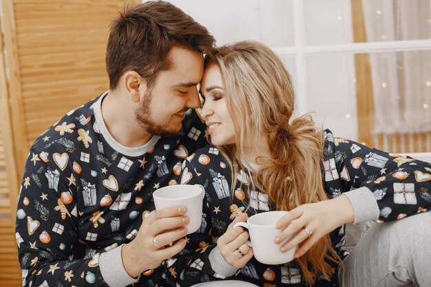 Mensen in een kerstversiering. Man en vrouw in een identieke pyjama. Familie op een bed.