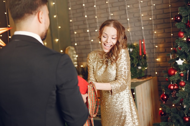 Mensen in een kerstversiering. Man in een zwart pak. Vrouw met rode doos.