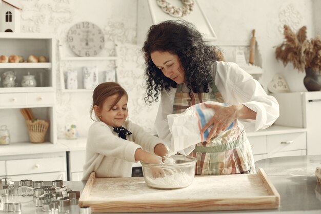 Mensen in een keuken. Grootmoeder met dochtertje. Volwassen vrouw leert meisje koken.