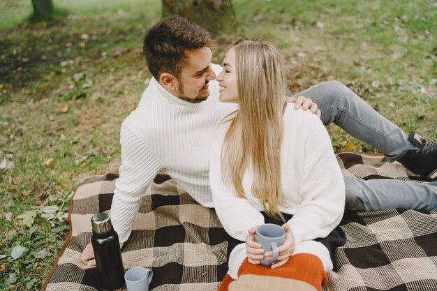 Mensen in een park. Vrouw in een bruine jas. Man in een witte trui. Koppel in een picknick.