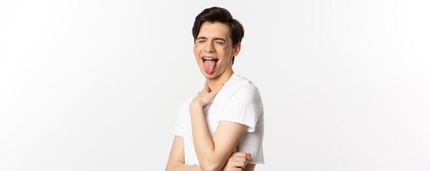 Mensen lgbtq en schoonheid concept close-up van zorgeloze homo man met glitter op gezicht tong tonen en grappig gezicht permanent op witte achtergrond maken