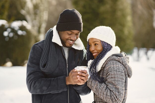 Mensen lopen naar buiten. Winter dag. Afrikaans echtpaar met koffie.