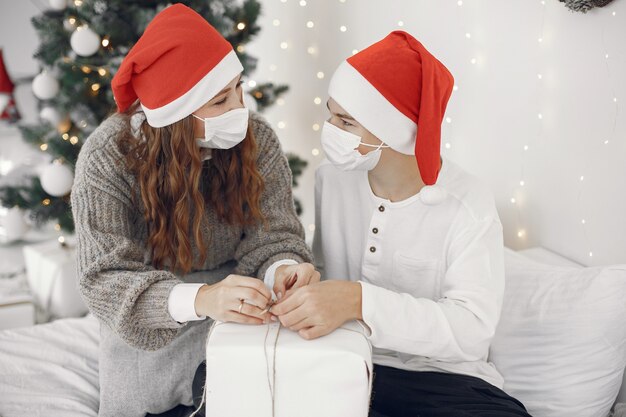 Mensen maken zich klaar voor Kerstmis. Coronavirus-thema. Moeder speelt met haar zoon. Jongen in een witte trui.