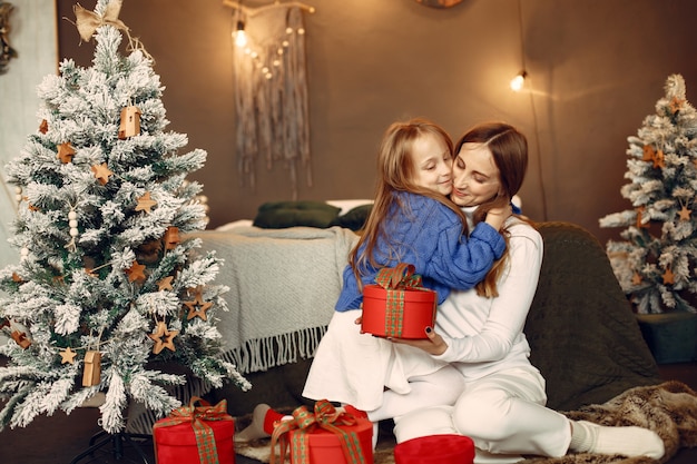Mensen maken zich klaar voor Kerstmis. Moeder speelt met haar dochter. Familie rust in een feestelijke kamer. Kind in een blauwe trui.