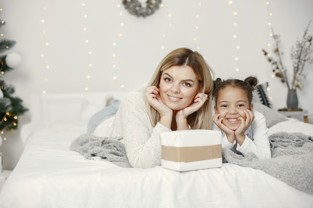 Mensen maken zich klaar voor Kerstmis. Moeder speelt met haar dochter. Familie rust in een feestelijke kamer. Kind in een sweatertrui.