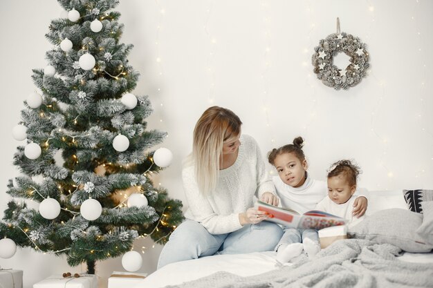 Mensen maken zich klaar voor Kerstmis. Moeder speelt met haar dochters. Familie rust in een feestelijke kamer. Kind in een sweatertrui.
