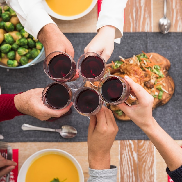 Mensen rinkelende wijnglazen boven feestelijke tafel