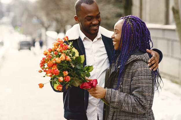 Mensen staan buiten. Man geeft bloemen voor vrouw. Afrikaans echtpaar. Valentijnsdag.