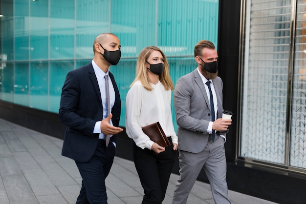 Mensen uit het bedrijfsleven in medische maskers lopen naar het kantoor