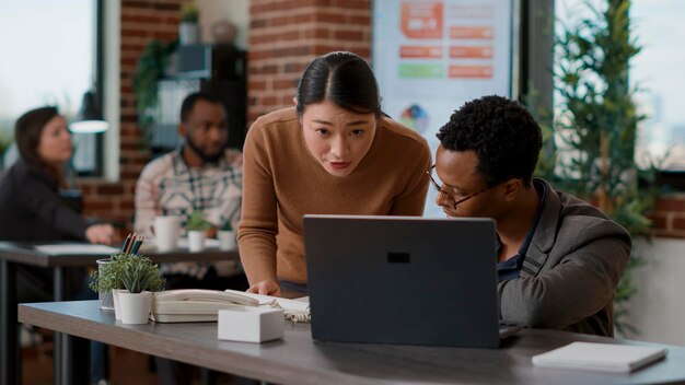 Mensen uit het bedrijfsleven kijken naar documenten, grafieken en laptop, met behulp van financiële statistieken om gegevensanalyse te maken. Team van werknemers die samen economie-presentatie plannen en werksamenwerking doen.