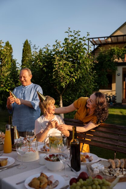 Mensen vieren een oudere verjaardagsfeestje buiten in de tuin