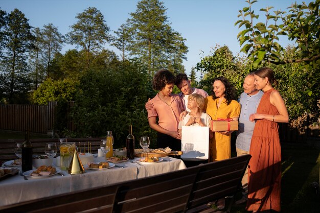 Mensen vieren een oudere verjaardagsfeestje buiten in de tuin