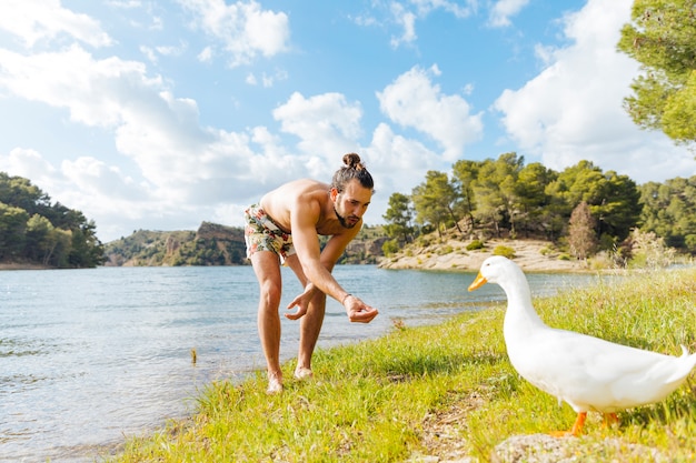 Gratis foto mensen voedende gans op kust