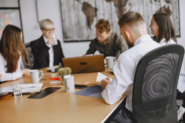 Mensen werken aan het project. Mannen en vrouwen in pakken aan tafel zitten. Zakenlieden gebruiken een laptop.