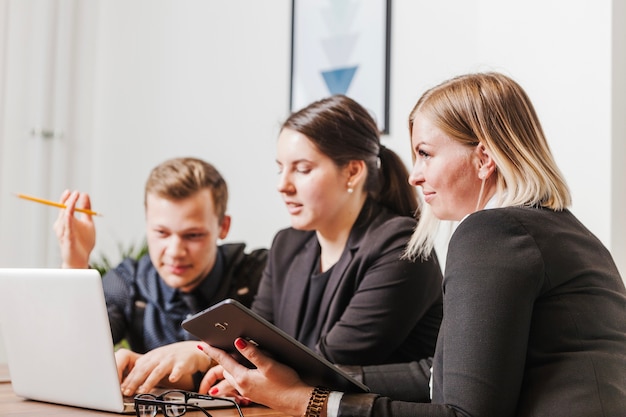 Gratis foto mensen zitten aan bureau werken op laptop