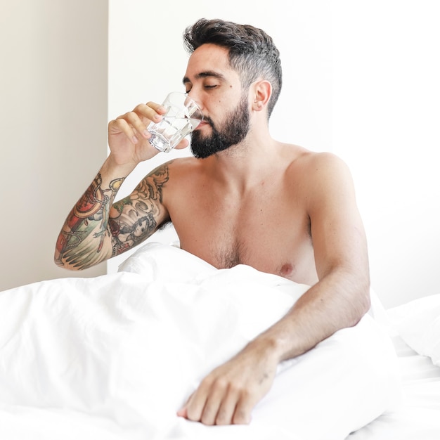 Mensenzitting op bed het drinken glas water