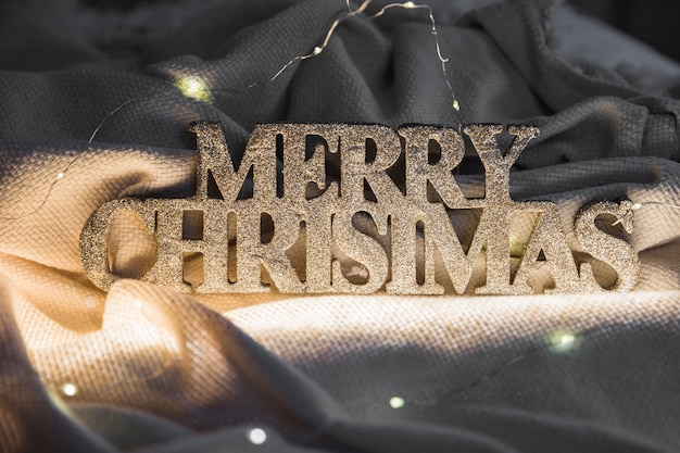 Gratis foto merry christmas inscriptie op coverlet tussen fairy lichten