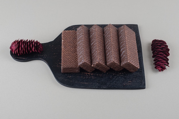 Met chocolade bedekte wafeltjes op een zwarte raad op witte achtergrond.