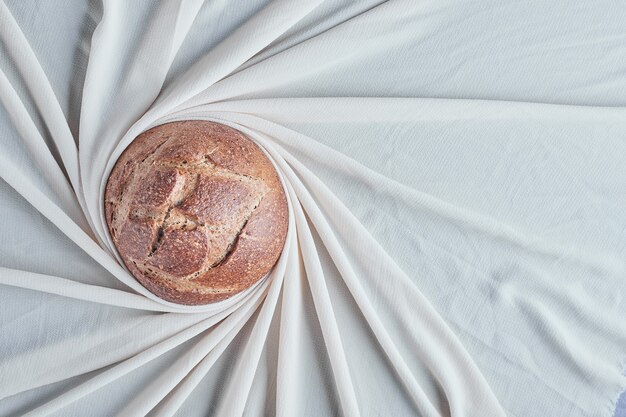 Met de hand gemaakt rond broodbroodje op grijs tafelkleed.