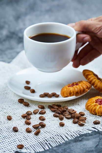 Met een kopje koffie met koekjes en koffiebonen.