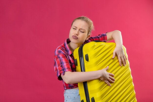 Met gesloten ogen reiziger jong meisje draagt rode shirt bedrijf koffer op geïsoleerde roze achtergrond