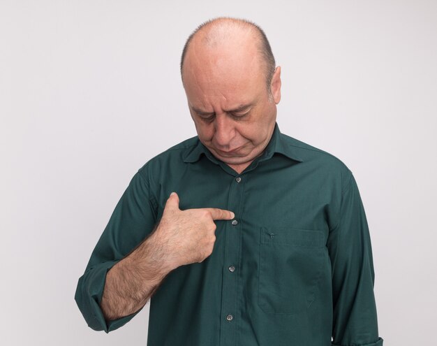 Gratis foto met verlaagd hoofd man van middelbare leeftijd dragen groene t-shirt zetten vinger zelf geïsoleerd op een witte muur