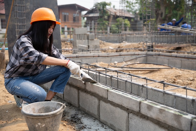 Metselaarwerknemer die baksteenmetselwerk op buitenmuur met troffelstopverfmes installeren