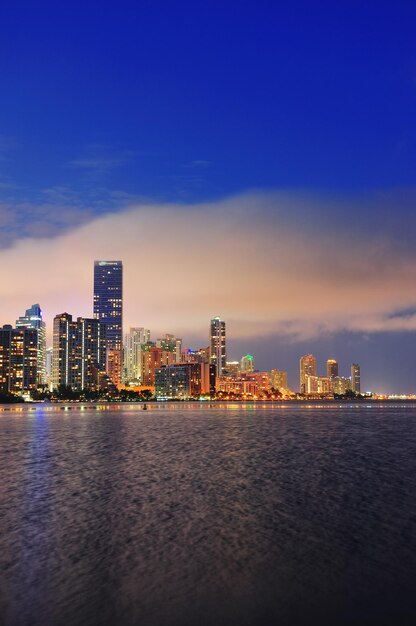 Miami skyline van de stad panorama in de schemering met stedelijke wolkenkrabbers over zee met reflectie