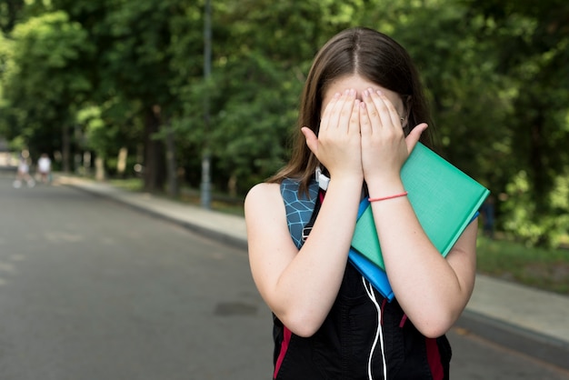 Middel dat van highschoolmeisje wordt geschoten die haar gezicht behandelen met handen