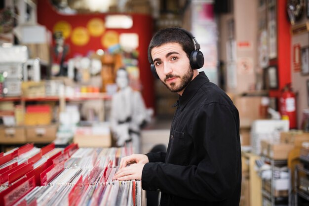 Middel geschoten zijaanzicht van de jonge mens die camera in vinylopslag bekijkt