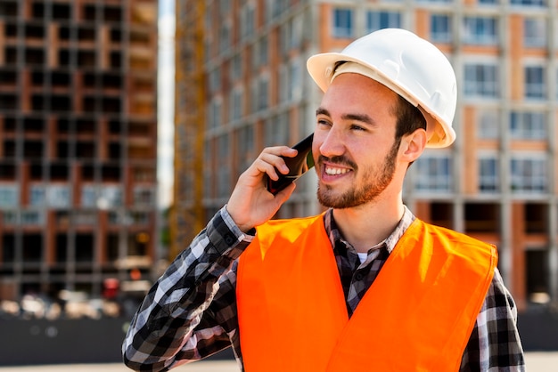 Gratis foto middel van bouwingenieur wordt geschoten die op de telefoon spreken die