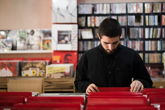 Gratis foto middel van jonge mens wordt geschoten die vinyls in opslag zoeken die