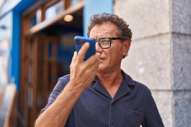 Middelbare leeftijd man praten op de smartphone op straat