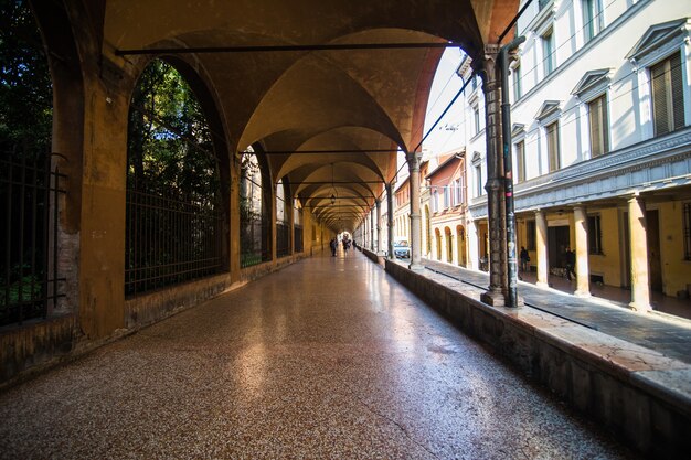 Middeleeuwse straatportiek met felgekleurde huizen in de oude stad in de zonnige dag, Bologna, Emilia-Romagna, Italië