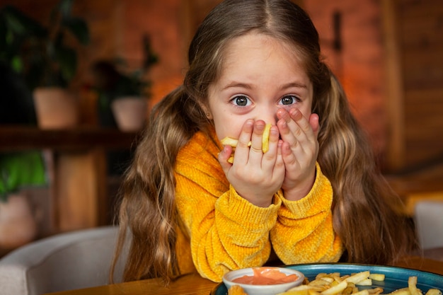 Middelgroot geschoten meisje dat frieten eet