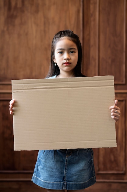 Gratis foto middelgroot geschoten meisje dat leeg aanplakbiljet houdt