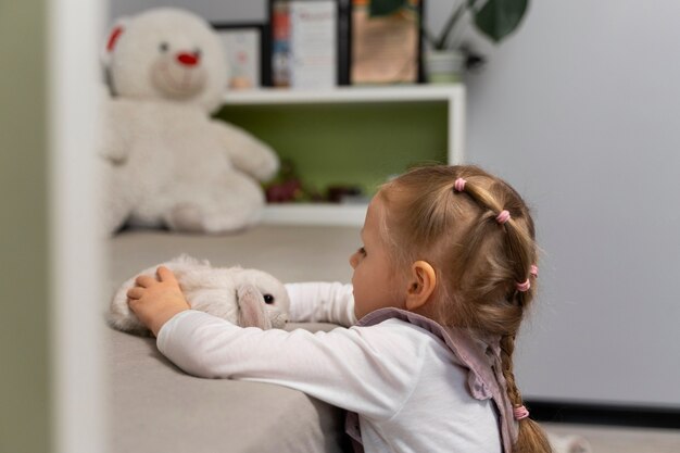 Middelgroot geschoten meisje dat met konijntje speelt