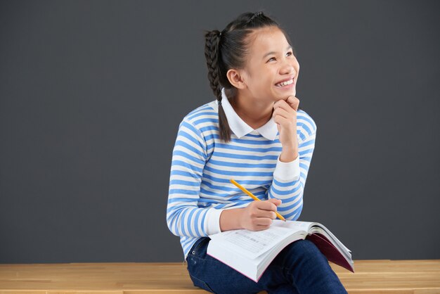 Middelgroot schot van Aziatisch schoolmeisje dat van huiswerk geniet