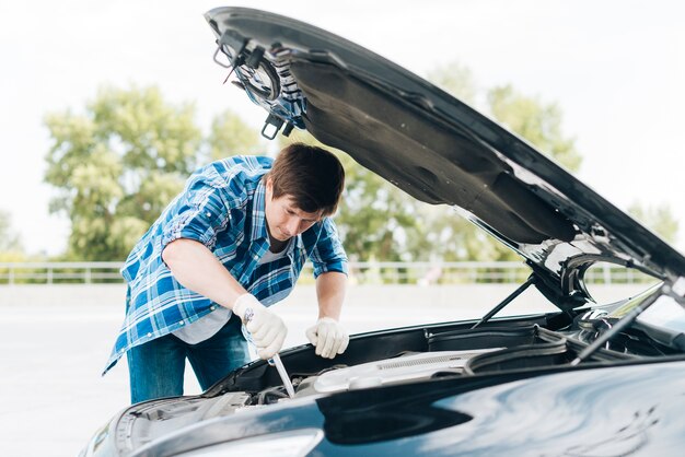 Middelgroot schot van de mens die motor herstelt