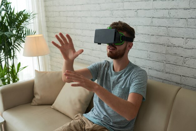 Middelgroot schot van de mens die VR-spel op de bank thuis spelen