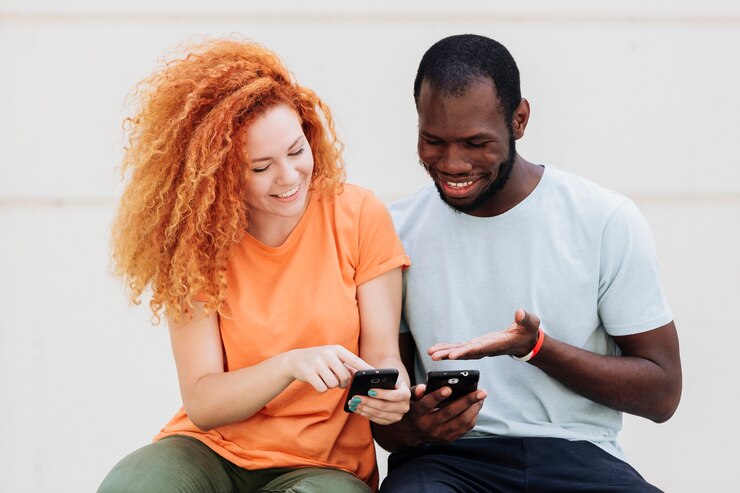Gratis Foto middelgroot schot van paar dat bij de telefoons lacht