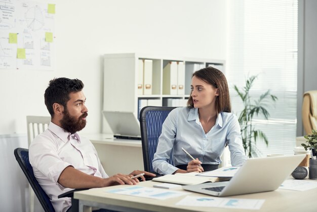 Middelgroot schot van twee collega's die zaken op het kantoor bespreken